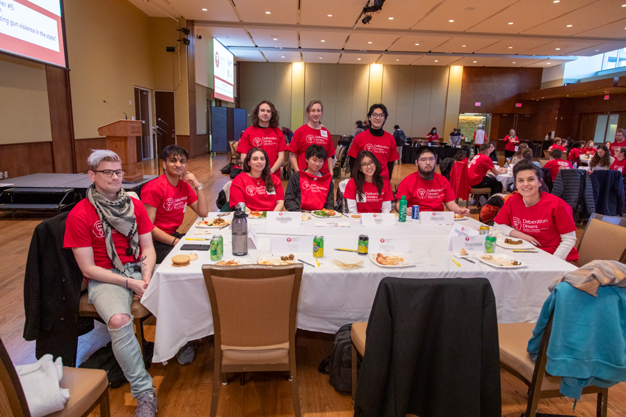 A table with 10 Deliberation Dinners students wearing red program t-shirts